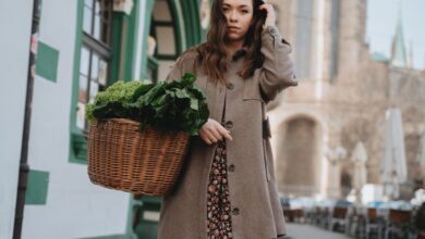 Food Urban Gardens - A woman in a brown coat carries a wicker basket of green vegetables while strolling through Erfurt, Germany.