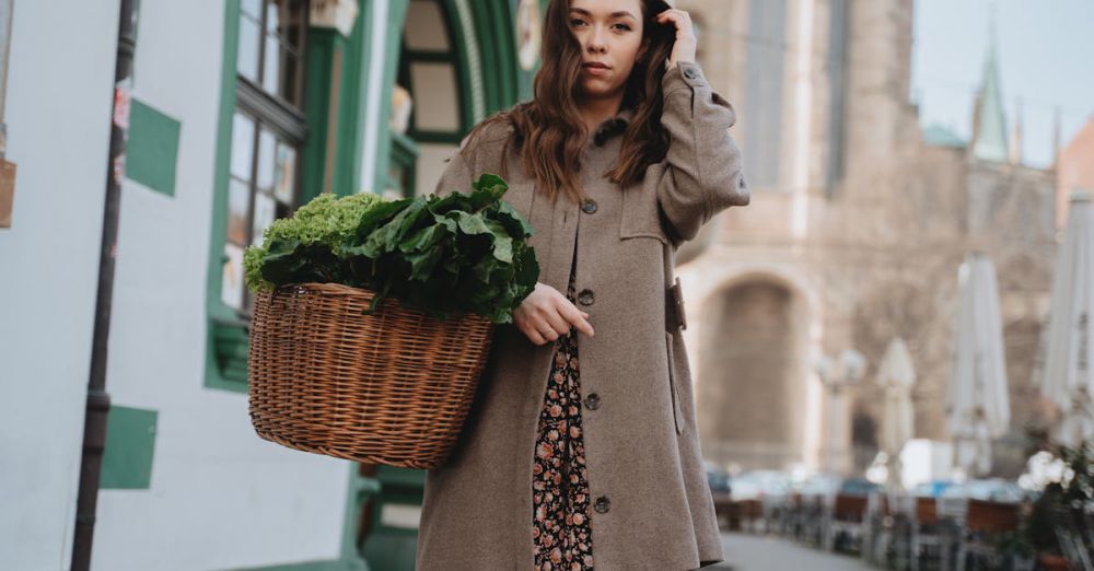 Food Urban Gardens - A woman in a brown coat carries a wicker basket of green vegetables while strolling through Erfurt, Germany.