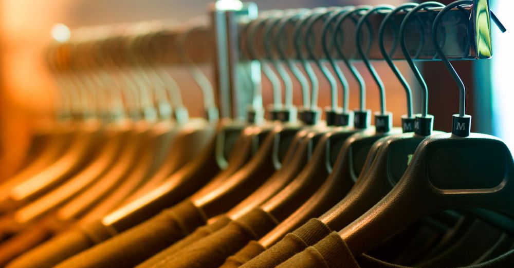 Clothing - A row of neatly arranged clothes hanging on a rack with wooden hangers.