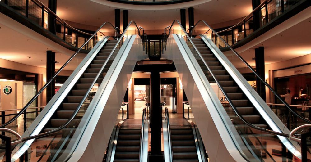 Malls - Symmetrical view of escalators in a modern shopping mall interior, showcasing architecture and design.