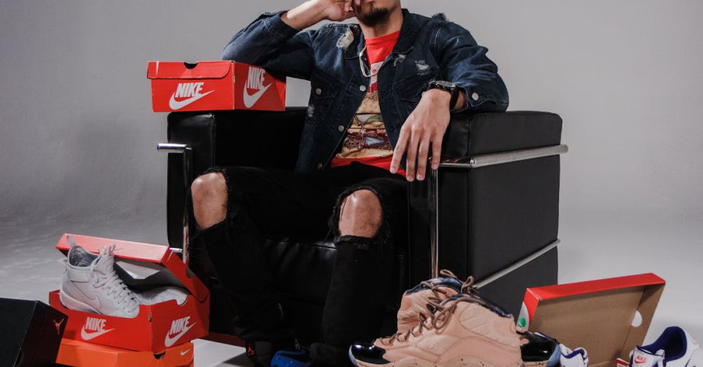 Brands - Fashionable man posing with a collection of branded shoes in a studio.