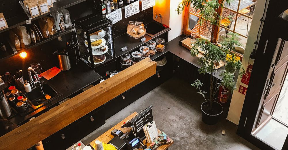 Goods - High angle view of a modern coffee shop interior with a wooden counter and cozy furnishings, ideal for business and leisure.