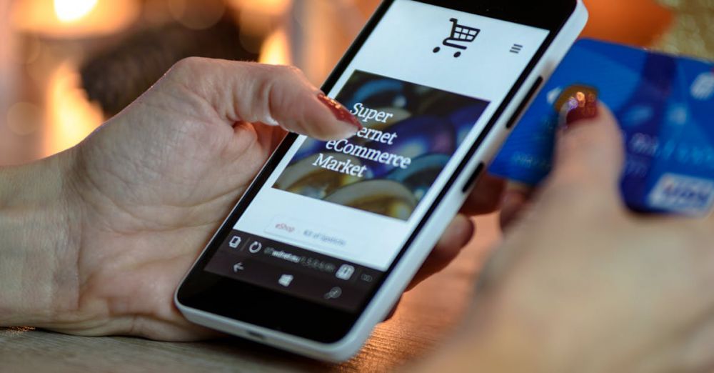 Shopping - Woman using smartphone for online shopping with credit card in hand, festive background lighting.