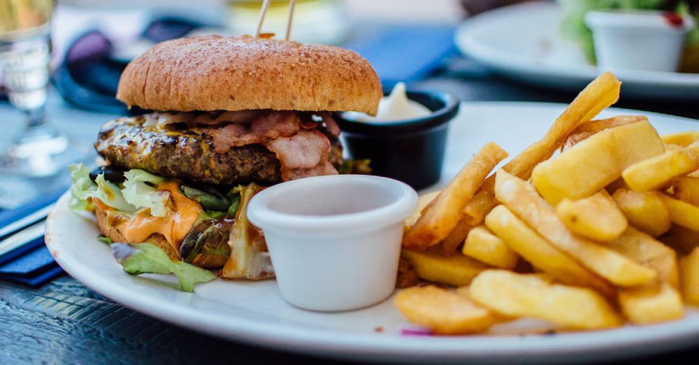 Food - Close-up of a juicy burger and crispy fries served with sauces, perfect for a hearty meal.