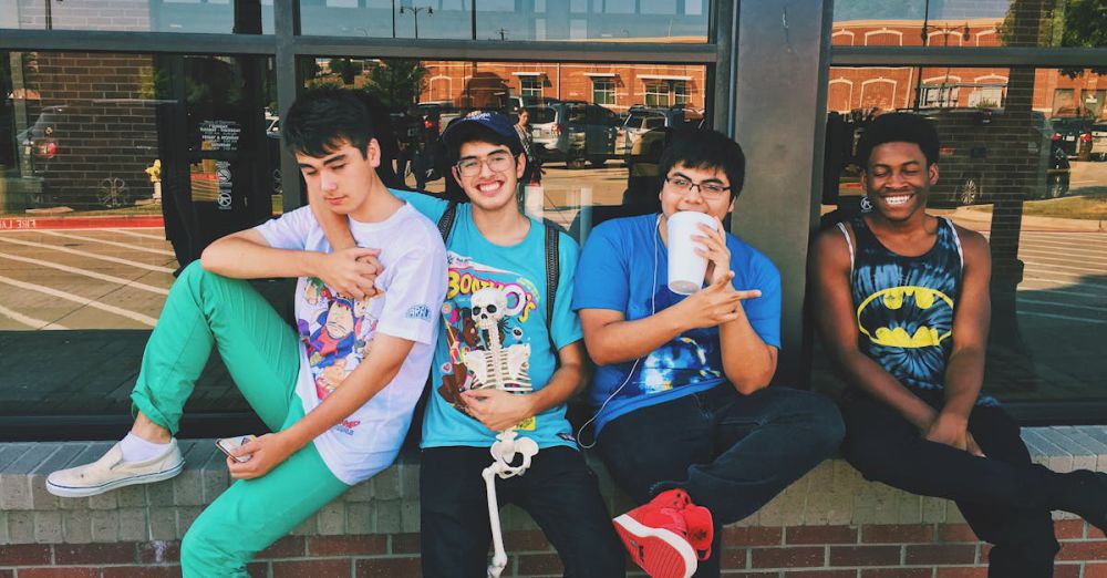 Teenagers - Group of teenage friends sitting outdoors, smiling and having fun together.