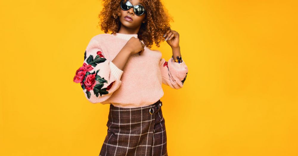 Fashion - Chic woman with afro hair in a floral sweater and plaid skirt posing confidently.