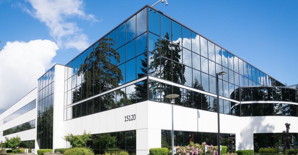 Companies - Contemporary office building in Redmond with reflective glass and lush greenery, captured on a sunny day.