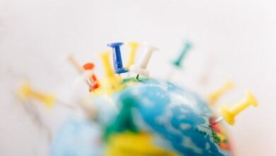 Locations - Vibrant close-up of a globe marked with multicolored push pins on a white background.