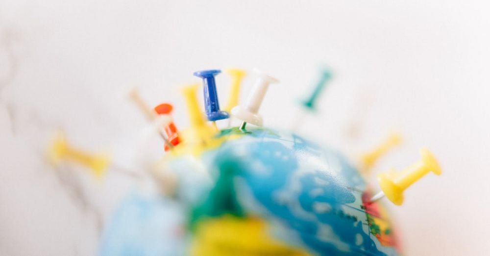 Locations - Vibrant close-up of a globe marked with multicolored push pins on a white background.