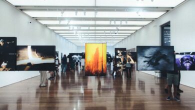 Arts - A contemporary art gallery with visitors observing various photographic exhibitions displayed on walls and stands.