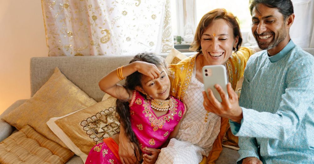 Tech Gifts - A joyful family in traditional clothing celebrates Diwali by taking a selfie together indoors.