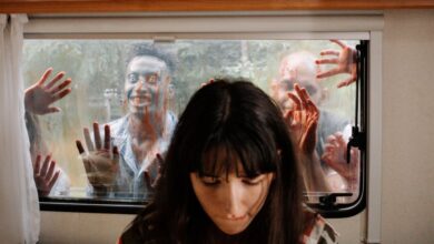 Shows - A woman sits unaware while terrifying zombies threaten through the window.