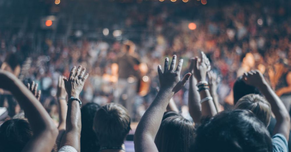 Events - Energetic crowd at a live concert with hands raised and bright lights.