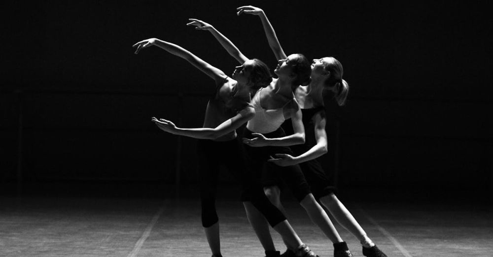 Dance - Three female ballerinas perform a synchronized dance on stage in dramatic lighting.