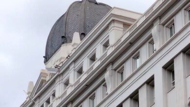 Theaters - Discover the intricate details of a historic building in Madrid, showcasing classic architecture against a cloudy sky.