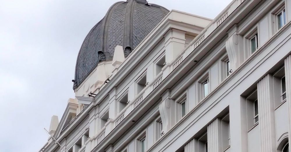 Theaters - Discover the intricate details of a historic building in Madrid, showcasing classic architecture against a cloudy sky.