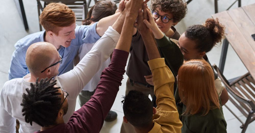 Companies - A diverse group of professionals high-fiving in a modern office, showcasing teamwork and collaboration.