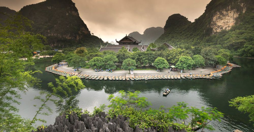 Tour - A scenic view of an island with boats, temple, and lush greenery in a tranquil setting.