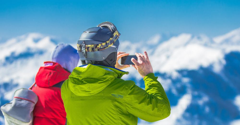 Tours - Two skiers capturing the breathtaking mountain views on a snowy winter day.