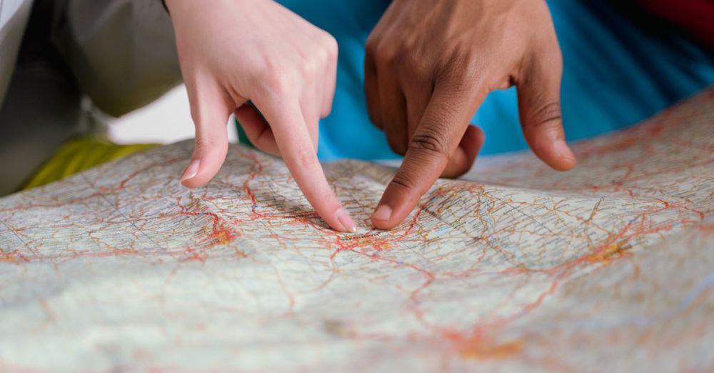 Locations - Close-up of diverse hands pointing at a paper map, symbolizing travel planning and navigation.