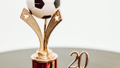 Sports Gifts - Shiny golden soccer trophy with ball and the year 20 on black surface.