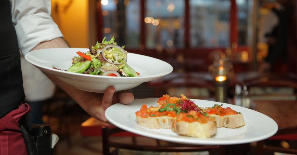 Candlelit - A waiter serves a fresh salad and hors d'oeuvres in a cozy restaurant setting.