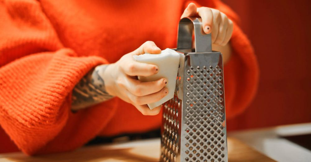 Shredders - Person grating bar of soap with metal grater in kitchen, showcasing a hygiene concept.