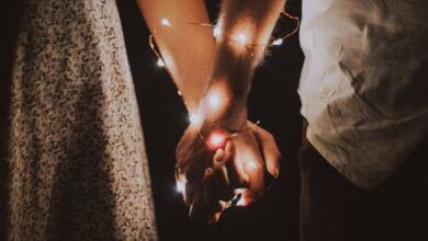 Couples - A warm and intimate close-up of a couple holding hands adorned with glowing string lights.