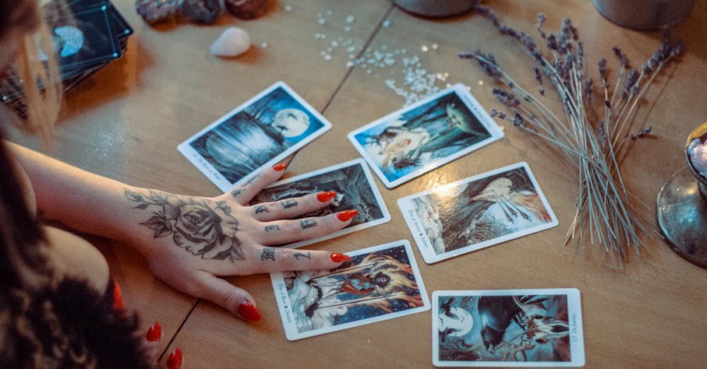 Psychic - A mystical setup featuring tarot card reading on a wooden table, with artistic tattoos and dried flowers.