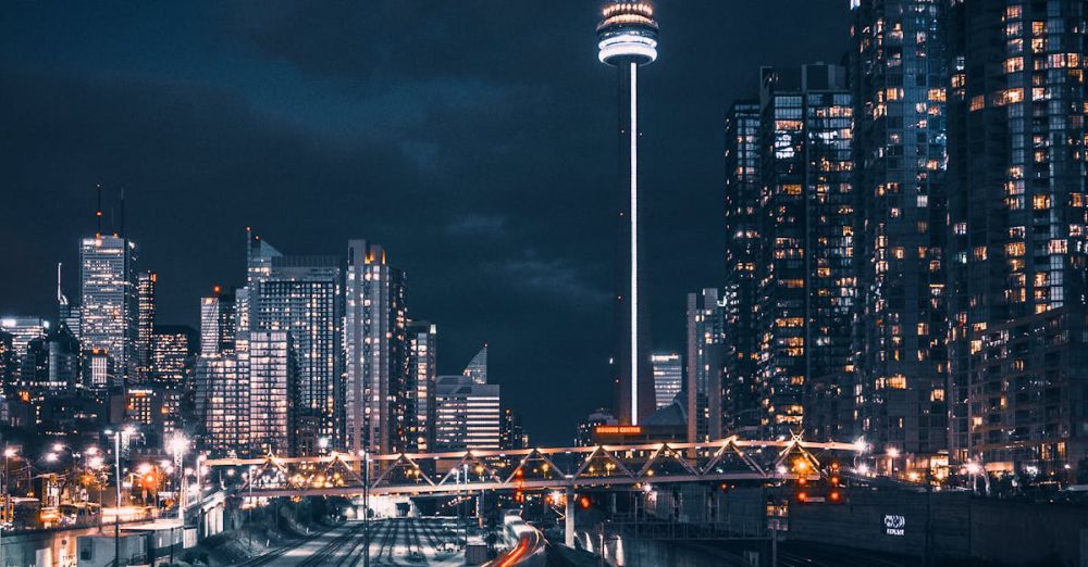 Locations - Stunning night view of Toronto skyline featuring the CN Tower and blurred train motion.