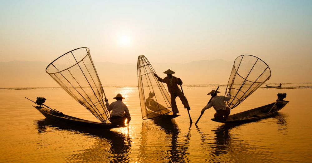Boat - Silhouetted fishermen on Inle Lake, Myanmar casting nets in the golden sunrise.