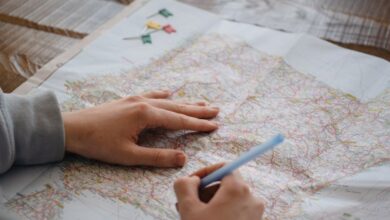 Routes - Individual marking destinations on a map with a pen while drinking water indoors.