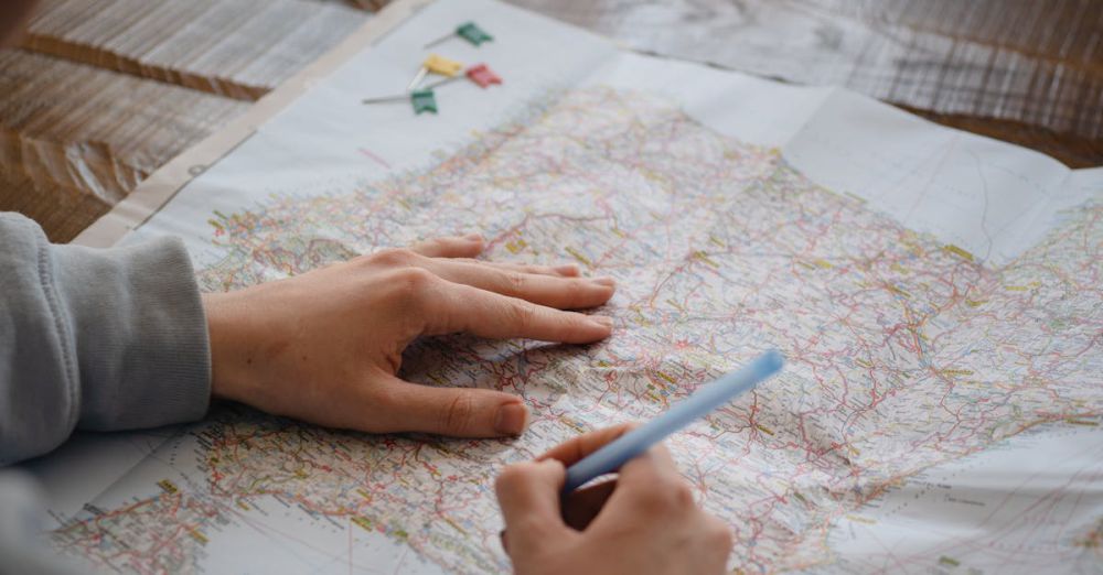 Routes - Individual marking destinations on a map with a pen while drinking water indoors.