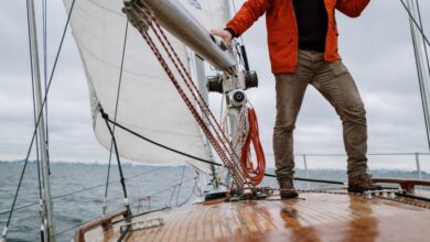 Boat - Man standing on a sailboat enjoying the journey with a vast horizon in the background.