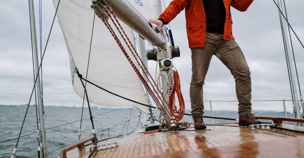 Boat - Man standing on a sailboat enjoying the journey with a vast horizon in the background.