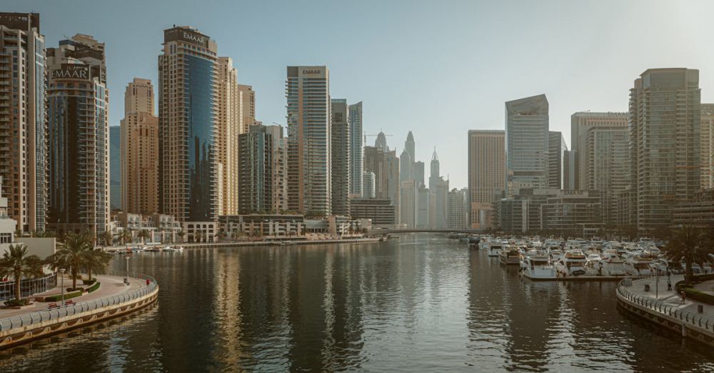 Marinas - Stunning view of Dubai Marina featuring skyscrapers and calm reflective waters under a clear sky.