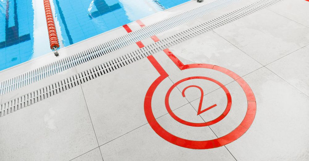 Competitions - Close-up of the number two marking beside an outdoor swimming pool lane.