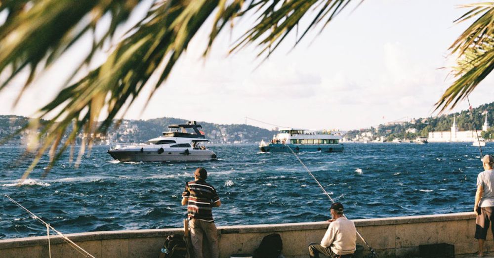 Destinations - Fishermen fishing by a vibrant waterside with boats and scenic backdrop. Perfect serene day outdoors.