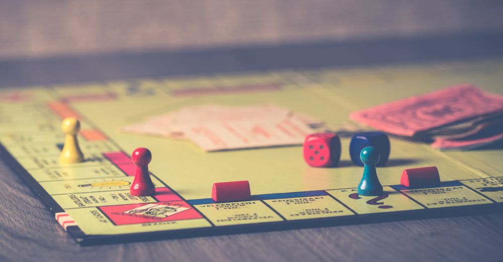 Board Games - A close-up of a Monopoly board game with pieces and dice scattered around.