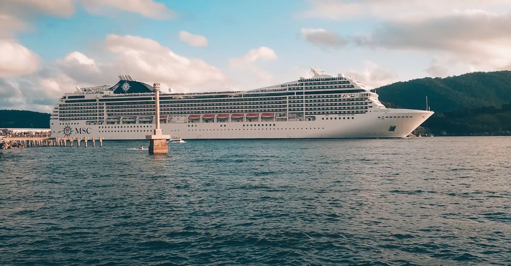 Cruise - A grand cruise ship sails under a bright blue sky with fluffy clouds over a calm ocean.