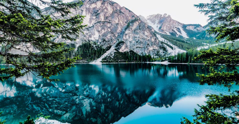 Lakes - Serene mountain lake with stunning reflections in Braies, Italy, surrounded by trees.