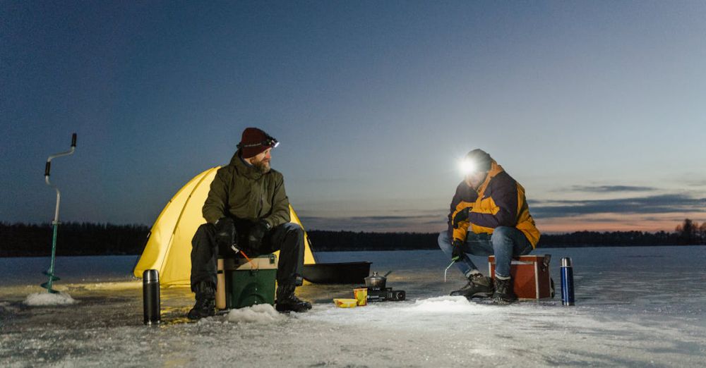 Fishing - Two men ice fishing by a tent during winter dusk. Adventure on a frozen lake.