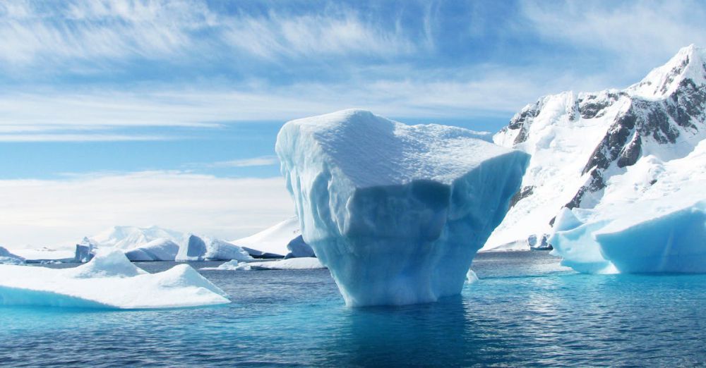 Arctic - A stunning iceberg floating in the cold, pristine waters with a backdrop of snowy mountains.