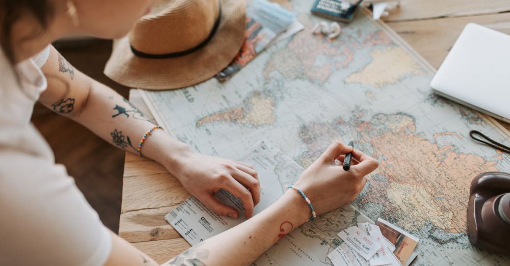 Routes - Person planning a journey with a map, passport, and travel essentials on a wooden table.