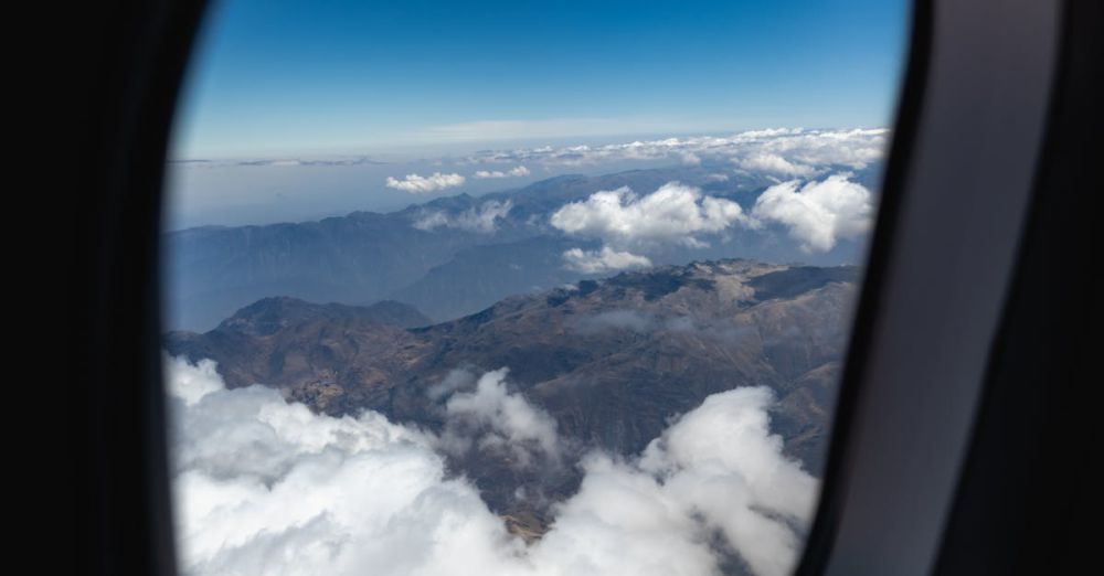 Trip - A breathtaking aerial view of clouds and mountains through an airplane window.