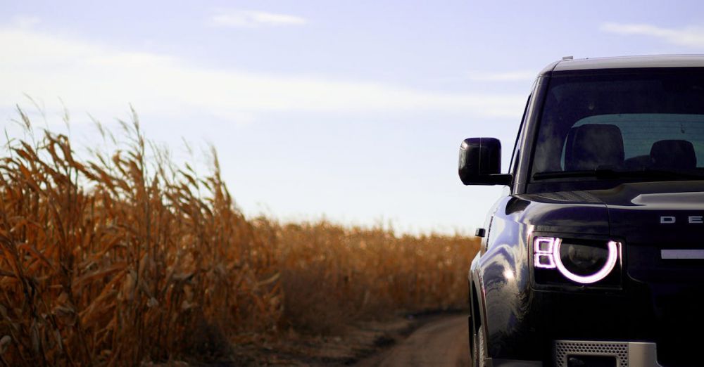 Backcountry - Stylish SUV on a dirt road beside a dry cornfield under an expansive sky, conveying adventure.