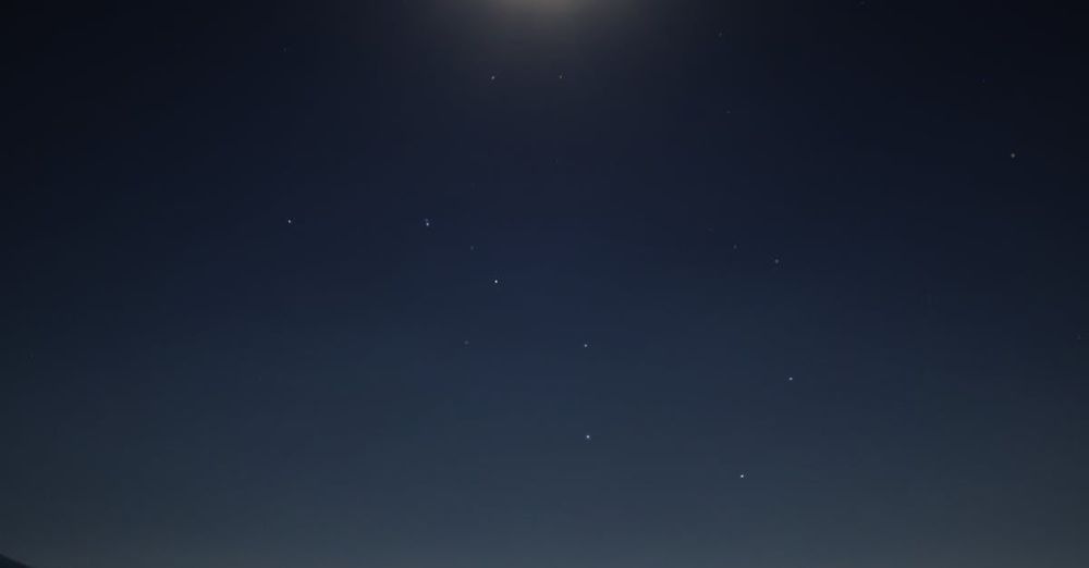 Stargazing - A person stands silhouetted against a moonlit night, stargazing in Brixen, Italy.