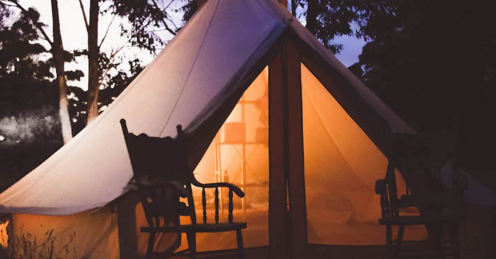 Glamping - Experience a serene glamping setup with glowing tent amidst Australian woods at dusk.