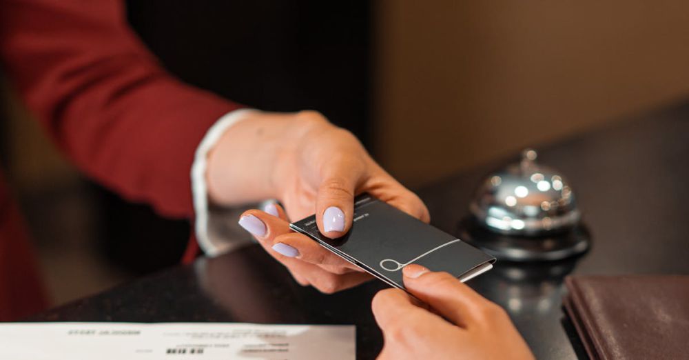 Reservation - A hotel receptionist hands a key card to a guest over the counter, with documents visible.