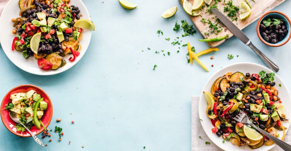 Cooking - Colorful Mexican salad with avocado, black beans, and lime on a light blue surface.